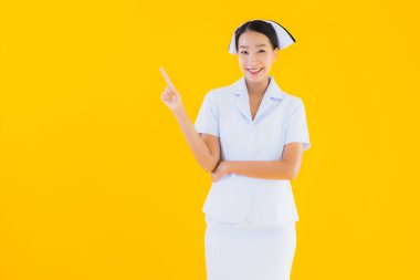 Güzel Asyalı genç Taylandlı hemşirenin portresi klinikteki ve hastanedeki hastalar için sarı izole edilmiş arka planda birçok eylem çalışmasında yer alıyor.