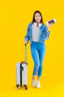 Güzel, Asyalı genç bir kadının portresi valiz ve pasaport ile seyahat, sarı izole arka planda biniş kartı.