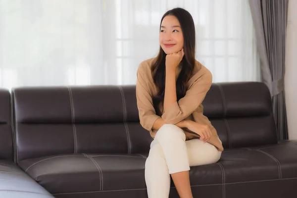 ポートレート美しい若いアジア人女性幸せな笑顔リラックス上のソファでリビングルームインテリア — ストック写真