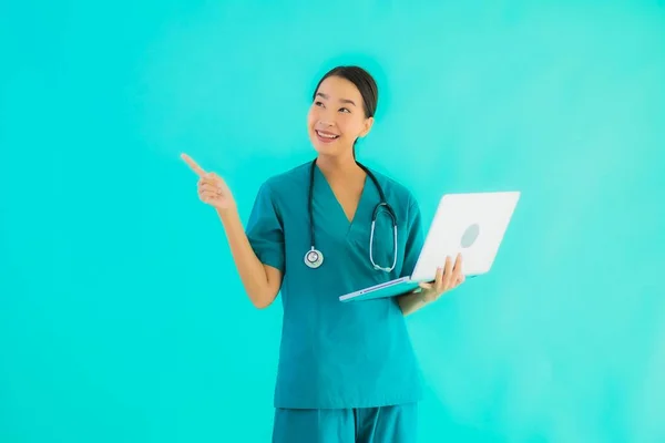 Portrait beautiful young asian doctor woman with laptop or computer on blue isolated background