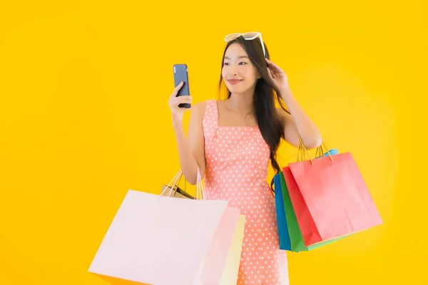 노란색외진 배경에 쇼핑백 스마트폰 신용카드가 아름다운 아시아 여성의 — 스톡 사진