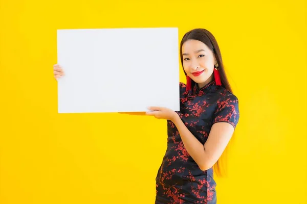 穿着中国服装的美丽的亚洲年轻女子形象在中国新年的概念中 在黄色孤立的背景下 展示了白纸空白字的广告牌 — 图库照片