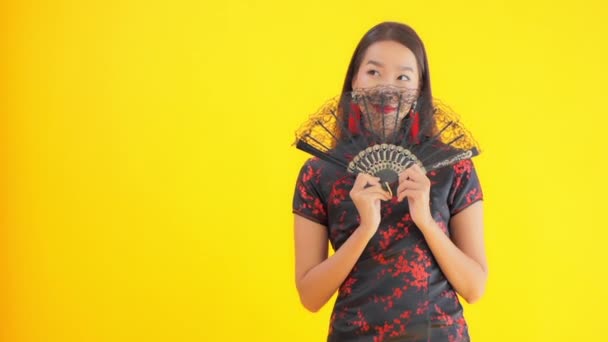 穿着中国传统服装 手持扇子 与黄色隔离的美丽年轻亚洲女子的特写镜头 — 图库视频影像