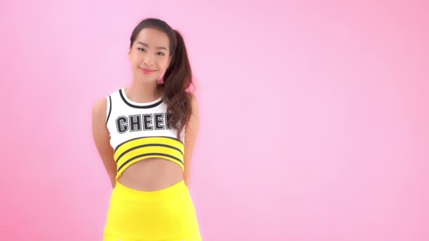 穿着啦啦队队长制服的漂亮年轻亚洲女子的特写镜头 用粉色隔开 — 图库视频影像