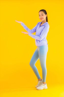 Sarı izole edilmiş arka planda spor giysili güzel Asyalı kadın portresi egzersize hazır.