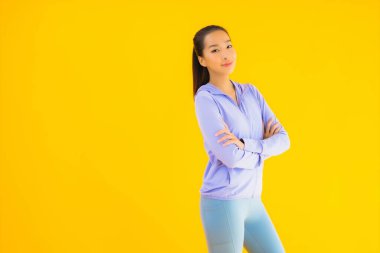 Sarı izole edilmiş arka planda spor giysili güzel Asyalı kadın portresi egzersize hazır.