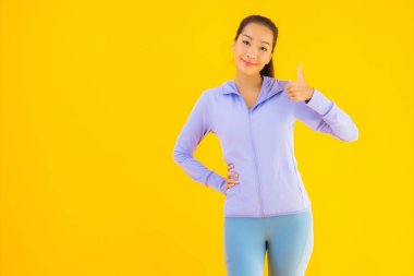 Sarı izole edilmiş arka planda spor giysili güzel Asyalı kadın portresi egzersize hazır.