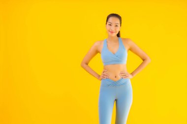 Sarı izole edilmiş arka planda spor giysili güzel Asyalı kadın portresi egzersize hazır.