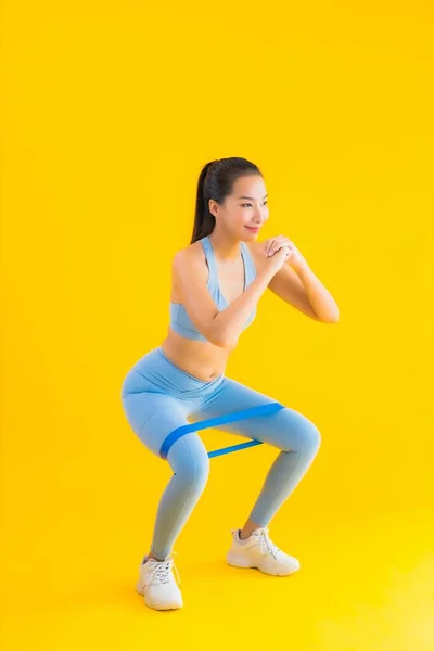 肖像美しい若いアジアの女性は黄色の隔離された背景に運動のための準備ができてスポーツゴムとスポーツウェアを着用 — ストック写真