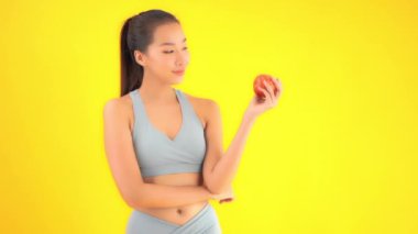 Sarı üzerine kırmızı elma izole edilmiş spor üstteki güzel Asyalı kadının görüntüleri.