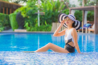 Güzel bir portre genç Asyalı mutlu bir gülümseme tatil beldesi otelinde havuzda rahatça yüzebiliyor.