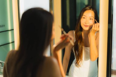 Güzel bir Asyalı kadın portresi makyaj malzemesi makyaj malzemesi ve yüz makyajı ile banyo içinde yüz maskesi.