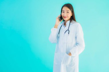 Güzel bir Asyalı doktor portresi. Klinik ya da hastane için cep telefonu kullanıyor.