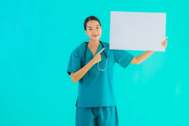 Fotokopi için boş kâğıt tahtası olan güzel Asyalı genç doktor kadın hastane ve klinikteki sağlık hizmetleri konseptinde mavi izole edilmiş arka plan.