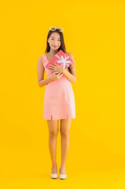 Sarı izole arka planda kırmızı hediye kutusu olan güzel Asyalı kadın portresi.