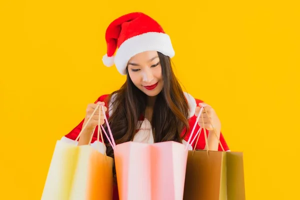 亚洲年轻貌美的女人 头戴圣诞礼帽 头戴黄色独立背景的购物袋 — 图库照片