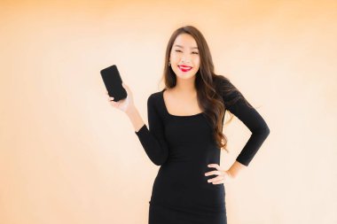 Güzel Asyalı genç bir kadının portresi mutlu bir şekilde gülümsüyor renkli arka planda akıllı cep telefonu kullan