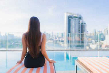 Güzel bir Asyalı kadının portresi tatil gezilerinde yüzme havuzunda rahatlar.