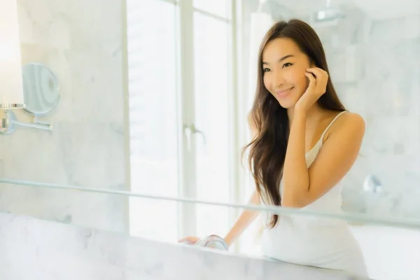 Portrait beautiful young asian woman check up and make up her face on mirror in bathroom interior