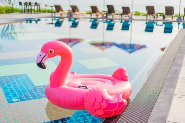 Flamingo, otel tatil beldesinde şemsiye ve sandalyeyle havuzda yüzer.