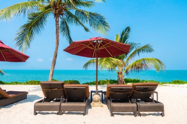 Güzel tropikal deniz okyanusu, şemsiyesi ve sandalyesi ile mavi gökyüzünde hindistan cevizi palmiyesinin etrafında tatil için