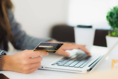 Güzel bir Asyalı kadının portresi online alışveriş malzemesi olarak dizüstü bilgisayarla kredi kartı kullanıyor.