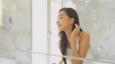 Güzel Asyalı bir kadının makyaj yaptığı ve aynaya baktığının görüntüleri.