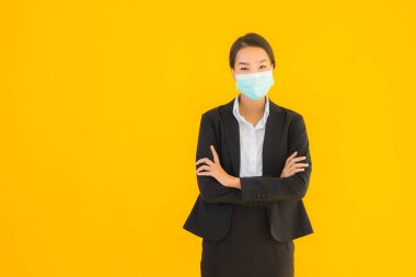 Güzel genç iş kadını portresi Korunmak için maske takıyor 19 koronavirüs sarı izole arka planda