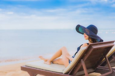 Güzel Asyalı genç kadınların portresi rahatlatıcı gülümseme deniz kıyısında mutlu bir tatil seyahati.