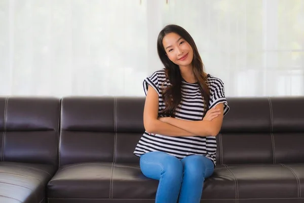 美丽动人的年轻亚洲女人快乐的笑着在客厅的沙发上放松一下 — 图库照片