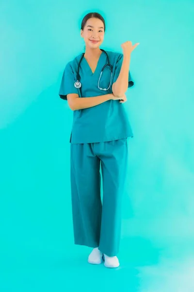 ポートレート美しい若いアジアの医師の女性幸せな笑顔のために病院やクリニックでの仕事上の青隔離された背景 — ストック写真
