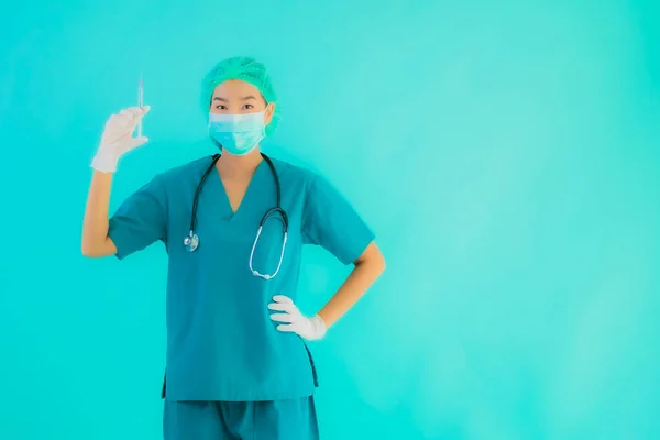 Portrait beautiful young asian doctor woman wear mask with syringe vaccine for protect from covid19 or coronavirus on blue isolated background