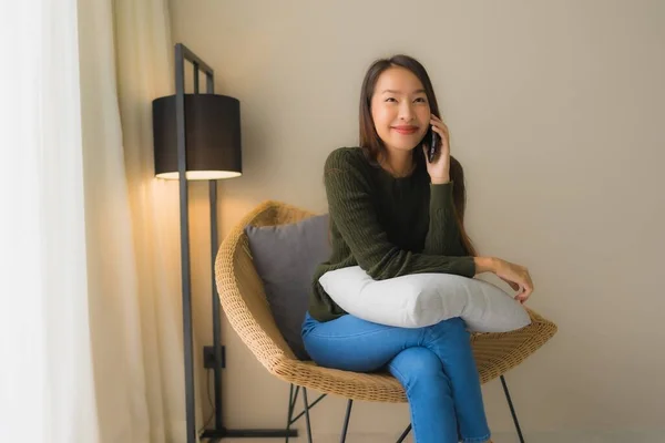 말하는 전화를 사용하고 거실에서 의자에 아름다운 여성의 — 스톡 사진