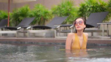 Güzel bir Asyalı kadın portresi otel havuzunda rahatça yüzebiliyor.