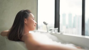 Güzel Asyalı bir kadının evde köpükle banyo yaptığı görüntüler.