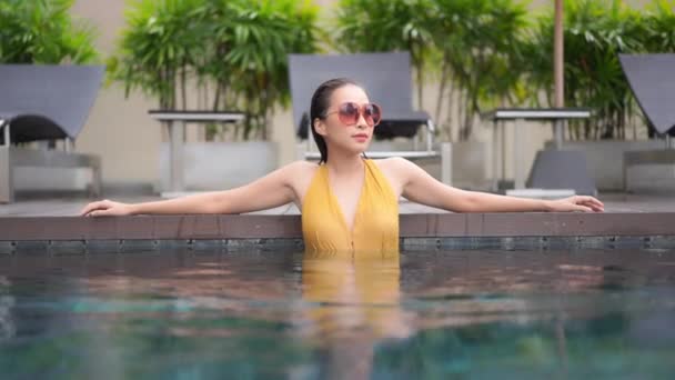 ポートレート美しい若いアジアの女性は ホテルのリゾートでスイミングプールの周りのレジャーをリラックス — ストック動画