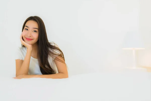 肖像画美しい若いアジアの女性リラックス幸せな笑顔でベッドの上に白い枕毛布インテリアのベッドルーム — ストック写真