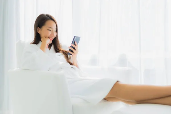 ポートレート美しい若いアジアの女性は リビングルームのエリアでソファにスマートフォンを使用します — ストック写真