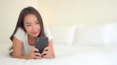 Evde akıllı telefon kullanan Asyalı güzel bir kadının görüntüleri.