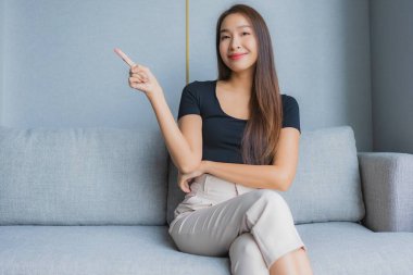 Güzel bir Asyalı kadın portresi. Kanepeye otur ve oturma odasında rahatla.