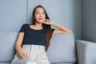 Güzel bir Asyalı kadın portresi. Kanepeye otur ve oturma odasında rahatla.