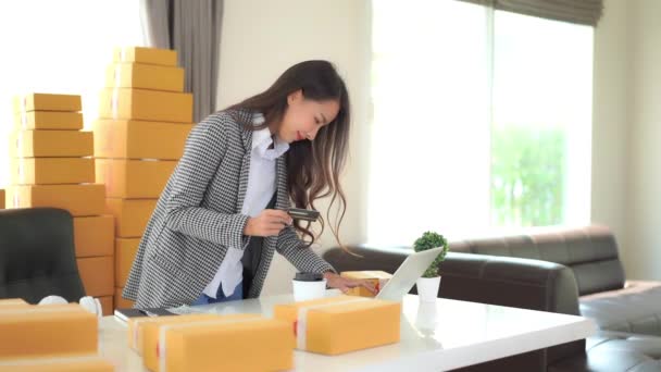 美丽的年轻亚洲女人带着成堆的包裹在家里干活的镜头 — 图库视频影像