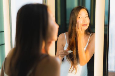 Güzel bir Asyalı kadın portresi. Banyo içinde yüzüne ve yüzüne krem sür.