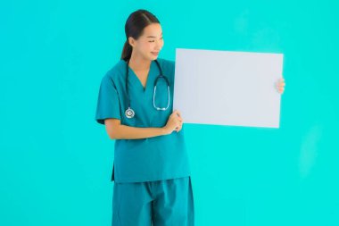 Fotokopi için boş kâğıt tahtası olan güzel Asyalı genç doktor kadın hastane ve klinikteki sağlık hizmetleri konseptinde mavi izole edilmiş arka plan.