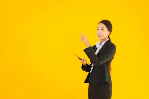 用黄色孤立背景的智能平板电脑刻画美丽的年轻亚洲女人快乐的微笑 — 图库照片