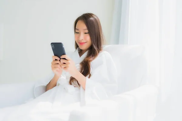 ポートレート美しい若いアジアの女性は リビングルームのエリアでソファにスマートフォンを使用します — ストック写真