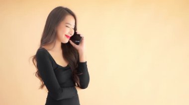 Güzel, genç Asyalı bir kadının bejde izole edilmiş bir şekilde telefonla konuştuğu görüntüler.