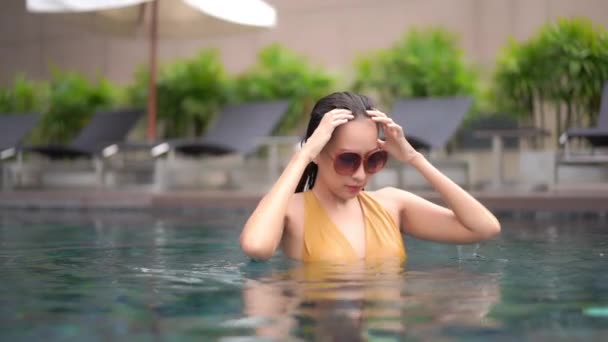 ポートレート美しい若いアジアの女性は休暇中のレジャーのためにホテルのリゾートでスイミングプールの周りリラックス — ストック動画