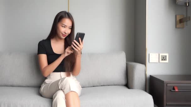 自宅でスマホを使って美しいアジア系女性の映像を — ストック動画