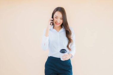 Akıllı cep telefonu ve kahve fincanı olan güzel bir iş kadını portresi.